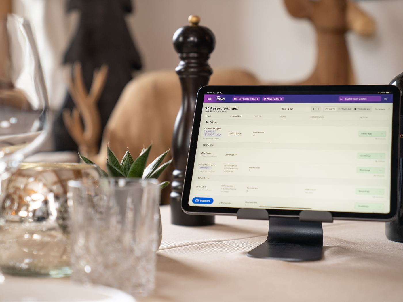 Reservierungsliste von Tably auf dem Tablet im Restaurant mit weißer Tischwäsche